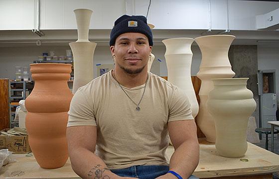 Gregory seated in front of large pottery