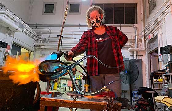 Bella in hot shop studio with blow torch, fire on glass object