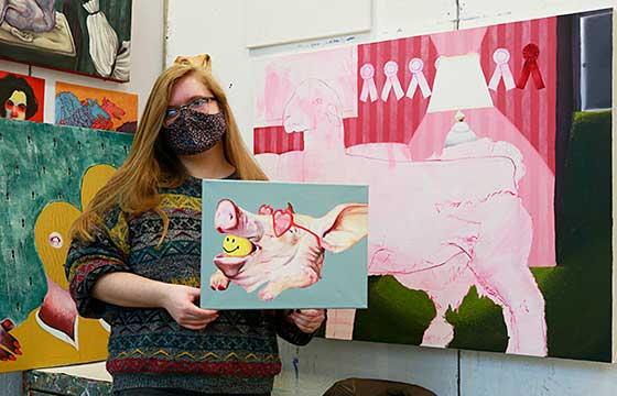 paige standing in studio in front of pink painting holding smaller painting pink on turquoise