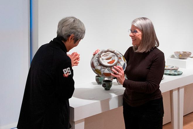 画廊工作人员向观众展示一件陶器