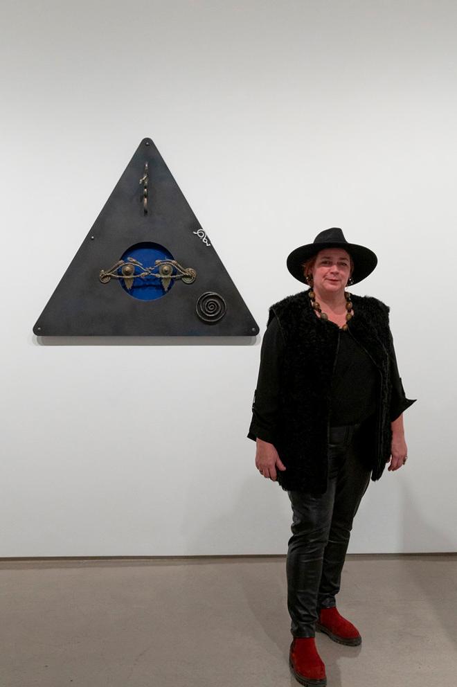 Artist Coral Lambert posing next to their artwork